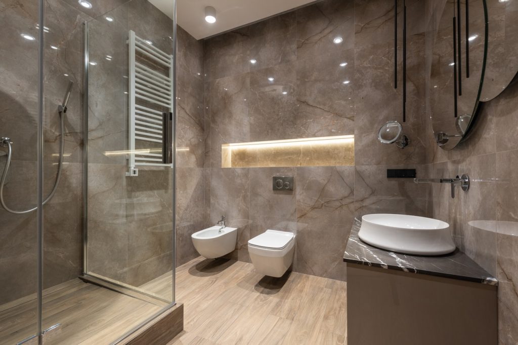 Spacious bathroom interior with shower cabin and shiny tiled walls